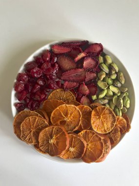 Mandalina ve çilek dilimler halinde kesilir ve tatlılar süslemek için kurutulur. Tabakta ayrıca antep fıstığı ve kurutulmuş kiraz lar da var..