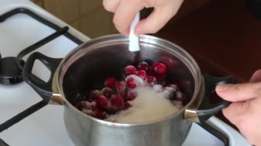 Bir adam şeker ve donmuş kızılcıkları bir tencerede karıştırır. Bir kaşıkla karıştırılır. Marshmallow için patates püresi hazırlar.