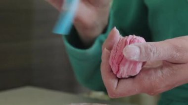 Bir kadın bir fırça ile bir marshmallow üzerine pudra şekeri uygular. Bir kenara koyun. Yakın çekim.