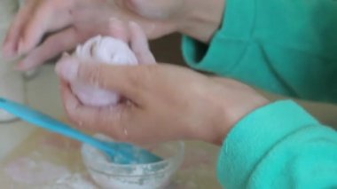 Bir kadın marshmallow iki yarısı katılır ve bir pasta fırçası kullanarak pudra şekeri ile davranır.