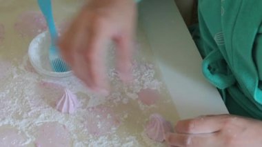 Bir kadın yemek kağıdından marshmallow kaldırır ve pudra şekeri ile davranır.