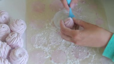 Bir kadın bir pasta fırçası kullanarak pudra şekeri ile marshmallow davranır. Yukarıdan görüntüle.