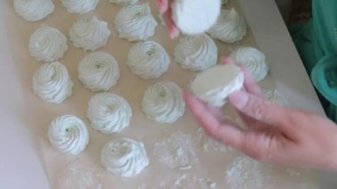 Yemek kağıdında, marshmallow pudra şekeri ile toz haline geldi. Bir kadın iş parçasını dener. Yukarıdan görüntüle.