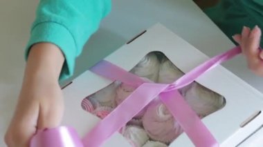 Bir kadın bir kutu şekerleme çalıyor. Kutudaki saydam pencereden görülebilen farklı renklerde marshmallow