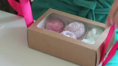 Bir kadın marshmallow hediye kutusunu çalıyor. Kutudaki saydam pencereden görülebilen farklı renklerde marshmallow.