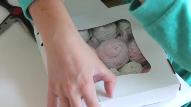 一个女人正在用绿松石辫子装一盒棉花糖 不同颜色的棉花糖 通过盒子里的透明窗口可见 — 图库视频影像
