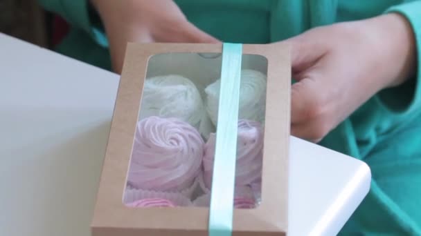 女性が自家製のマシュマロで箱の上に三つ編みを結んでいます ギフトボックスに異なる色のマシュマロ — ストック動画
