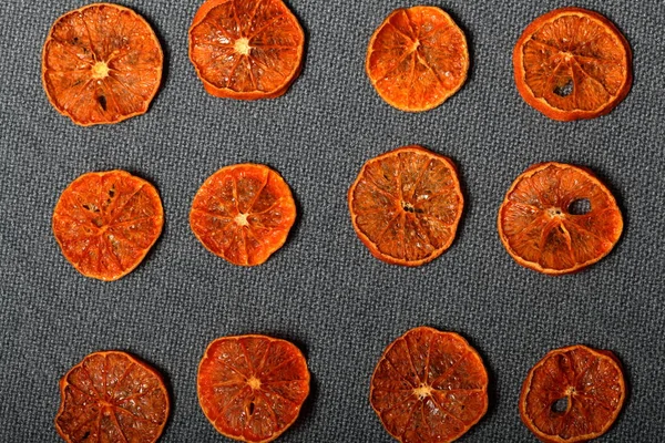 As tangerinas são cortadas em fatias e secas para decorar sobremesas. Em um fundo cinza . — Fotografia de Stock