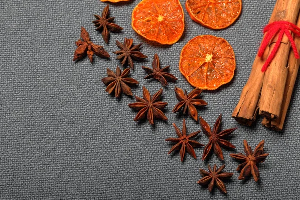 Mandarini secchi, tagliati a pezzi per decorare il dessert. Nelle vicinanze si trovano anice e bastoncini di cannella legati con filo rosso. Su uno sfondo grigio . — Foto Stock