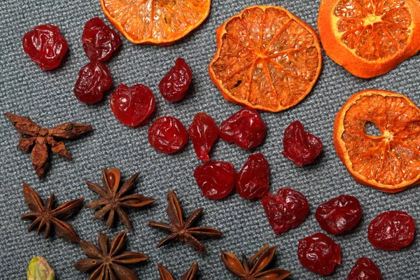 Dried tangerines and strawberries, cut into pieces to decorate the dessert. Nearby are dry cherries, pistachios and anise stars. — Stock Photo, Image