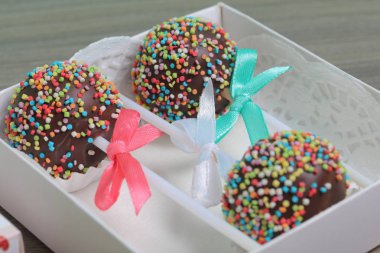 Renkli sprinkles ile çikolata Kek Pops. Kurdele yayı ile dekore edilmiştir. Hediye kutusunda yatıyorlar..