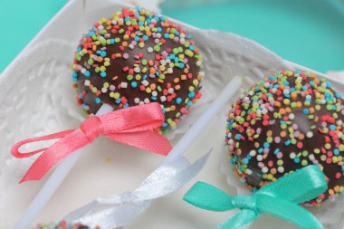 Renkli sprinkles ile çikolata Kek Pops. Kurdele yayı ile dekore edilmiştir. Hediye kutusunda yatıyorlar. Nane arka planında.