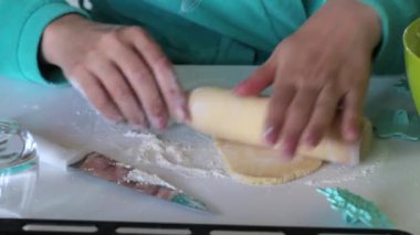 Bir kadın oklava ile marshmallow sandviç yapmak için hamur rulo. Yakındaki hamur üzerinde süs uygulamak için formlar vardır.