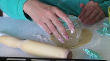 Camlı bir kadın yuvarlanan hamurdan yuvarlak boşlukları keser. Marshmallowlu sandviç yapmak için. Yakındaki hamur üzerinde süs uygulamak için formlar vardır