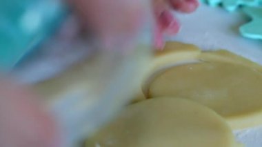 Camlı bir kadın yuvarlanan hamurdan yuvarlak boşlukları keser. Marshmallowlu sandviç yapmak için. Yakındaki hamur üzerinde süs uygulamak için formlar vardır.