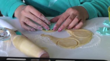 Pulu olan bir kadın, yuvarlanmış hamurun yuvarlak boşluklarına süs uygular. Marshmallowlu sandviç yapmak için.