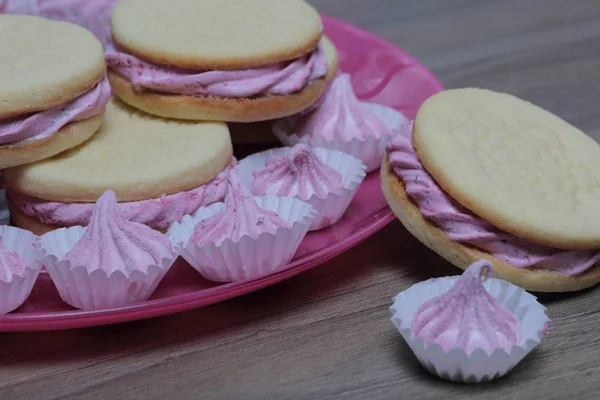 Cooked marshmallow sandwiches. They lie on plate. Next on the plate is a marshmallow of various sizes.