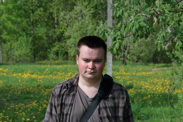 Portret pulchny młodego mężczyzny. Na wiosennej łące z jasną zieloną, młodą trawą i drzewami. — Zdjęcie stockowe