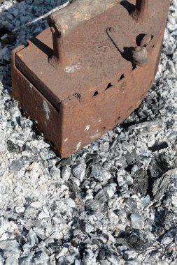 Kömürler üzerinde çalışan nadir demir. Soyu tükenmiş kömürlerin arka planına karşı.