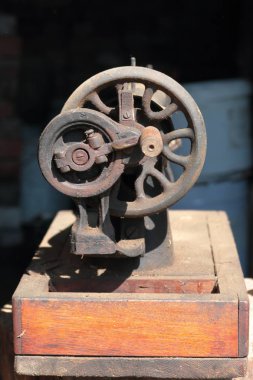 Eski dikiş makinesi, manuel sürücülü. Korozyon, toz ve örümcek ağları ile kaplı.