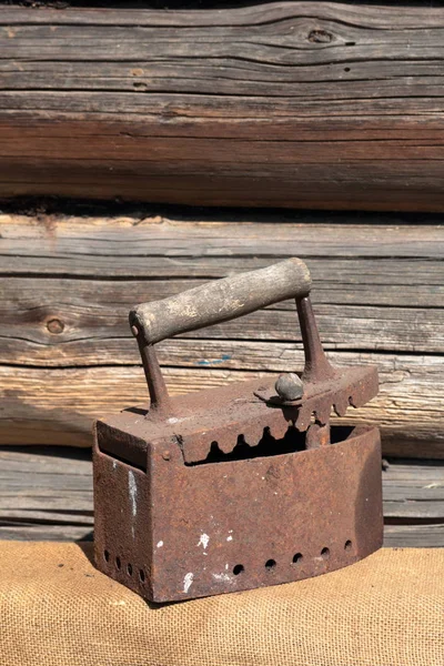 Hierro raro trabajando en carbones. Se encuentra en el fondo de un antiguo granero de madera. Se apoya en un paño grueso . — Foto de Stock