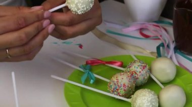 Bir kadın bir tabak üzerinde yatan örgü pasta pops yay süsler. Şeker pansuman ile süslenmiş.