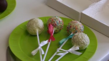 Bir kadın bir tabak üzerinde yatan örgü pasta pops yay süsler. Şeker farklı renklerde saçılma ile dekore edilmiştir. Hediye paketleme için kutunun yanında.