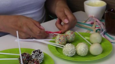Ev yapımı kek pops ambalaj önce tabaklarda yalan. Şeker siyah beyaz çikolata ile kaplı. Çeşitli tepesi ile. Bir kadın kurdelelerle süsler..
