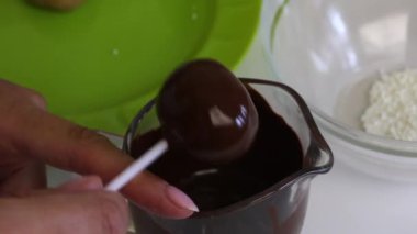 Kadın siyah çikolataya haşhaşlı kek batırıyor. Sırada pasta çubuğu var.