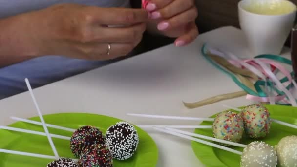 自制蛋糕在包装前放在盘子上 糖果上覆盖着黑白巧克力 与各种浇头 一个女人准备用辫子装饰它们 — 图库视频影像