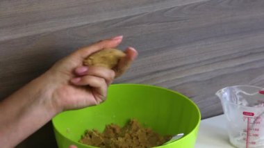 Bir kadın elinde yoğunlaştırılmış süt ile bisküvi topları rulo. Hazır toplar tabakta. Kek pops için pişirme temelleri.