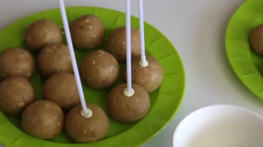 Bir kadın erimiş beyaz çikolata içine sopa dips ve bir popcake kütük onu düzeltir.