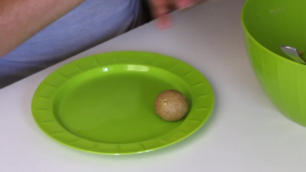 女性は 彼女の手に凝縮ミルクでビスケットのボールを転がします 彼は完成したボールを皿の上に置く ケーキポップの料理の基本 — ストック動画