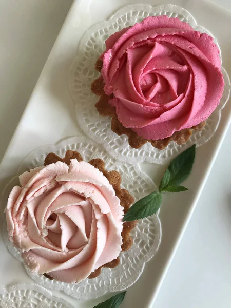 Keranjang kue. Dihiasi dengan krim keju mawar dan daun mint. Ditumpuk di piring putih persegi panjang. Lihat dari atas . — Stok Foto