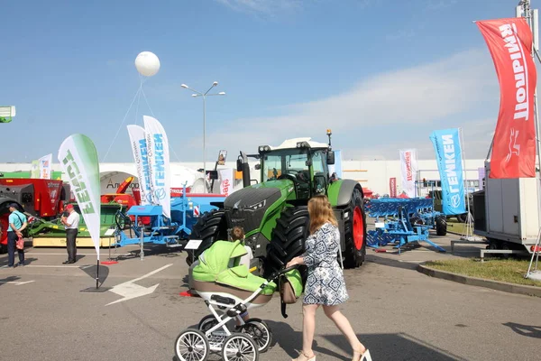 민스크, 민스크, 벨라루스 6 6 월 2019, 전시회 벨라그로 2019에서 박람회. 휠체어를 탄 아이를 가진 어머니가 전시회를 바라보고 있다.. — 스톡 사진