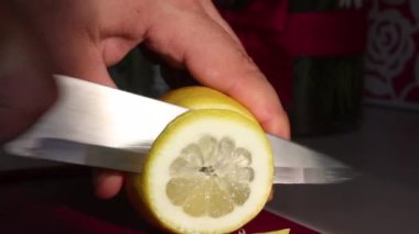 Adam limon yüzüklerini keser ve bıçağı bir kenara koyar. Limon taze ve sulu. Yakın çekim. Görünür etli limon hamuru, akan suyu.