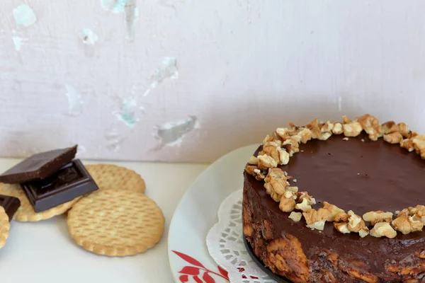 Cake without baking cookies and chocolate. Decorated with walnut crumbs. On a shabby aged background.