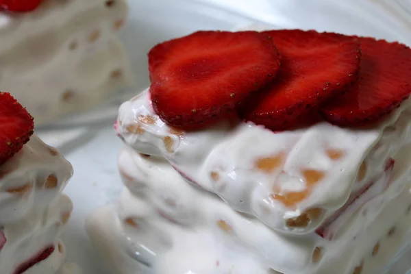 ビスケット、サワークリーム、イチゴのケーキ。イチゴのスライスで飾られています。皿の上に横たえる. — ストック写真