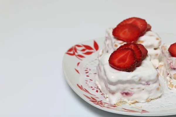 Pasteles de galletas, crema agria y fresas. Decorado con rodajas de fresa. Acuéstese en un plato . — Foto de Stock