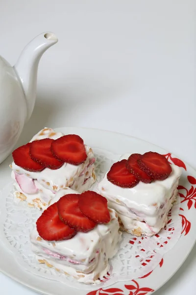 Κέικ με μπισκότα, ξινή κρέμα και φράουλες. Διακοσμημένο με φέτες φράουλας. Κοντά υπάρχει μια τσαγιέρα. — Φωτογραφία Αρχείου
