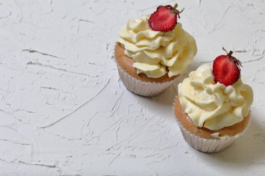 Çilek ve tereyağı krema ile Cupcakes. Dekoratif sıva ile beyaz bir yüzey üzerinde.