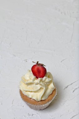Çilek ve tereyağı krema ile Cupcakes. Dekoratif sıva ile beyaz bir yüzey üzerinde.