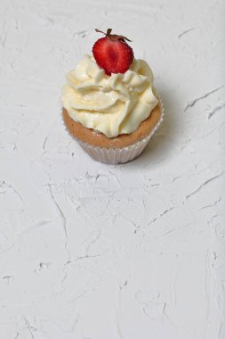 Çilek ve tereyağı krema ile Cupcakes. Dekoratif sıva ile beyaz bir yüzey üzerinde.