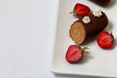 Patates kek krema ile süslenmiş. Görünür pasta dilimi. Yakında dekorasyon için çilek yarısı vardır.