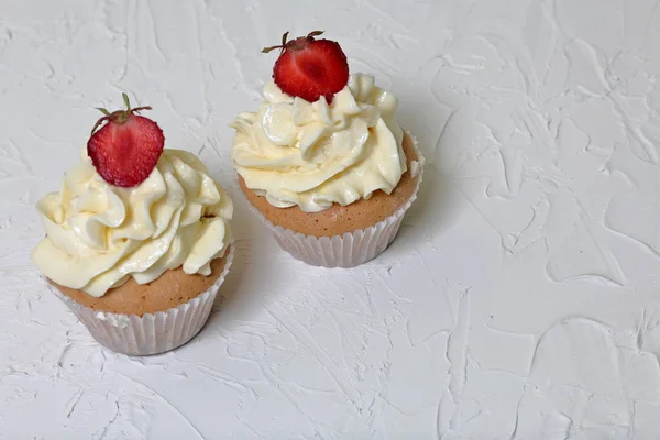 Gâteaux aux fraises et crème au beurre. Sur une surface blanche avec du plâtre décoratif . — Photo