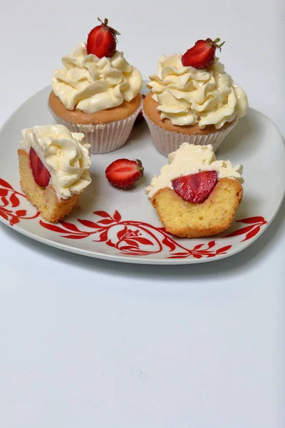 Cupcakes with strawberries and butter cream. One is cut in half. Visible filling. — Stock Photo, Image