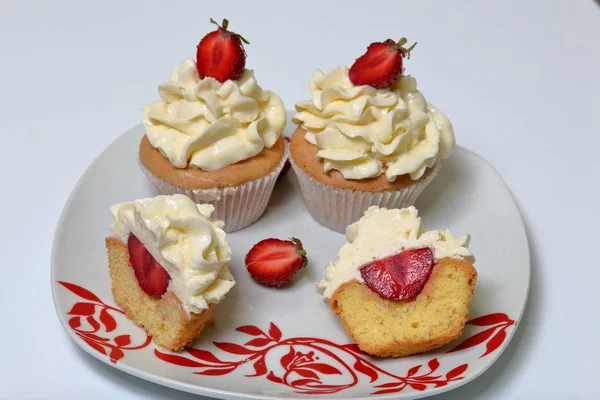 Cupcakes with strawberries and butter cream. One is cut in half. Visible filling. — Stock Photo, Image