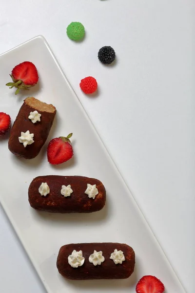 Potato cake decorated with cream. Visible slice of cake. Nearby are the halves of strawberries and colored berries for decoration.