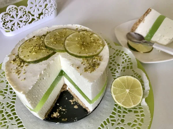 Limoen Cheesecake zonder bakken. Versierd met kalk schijfjes. Het stuk wordt afgesneden. Ligt op een bord. — Stockfoto