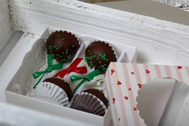 Kek bir hediye kutusuna paketlenmiş, örgü bir yay ile süslenmiş açılır. Beyaz boyalı ahşap bir kutuda.